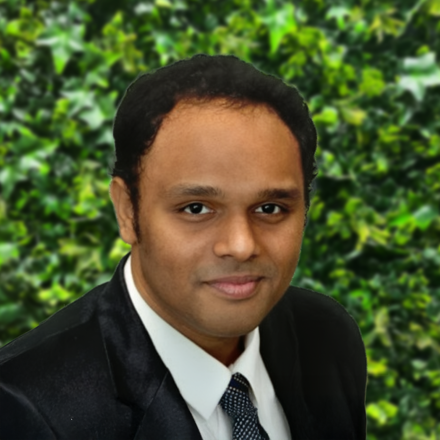 Man in suit smiling before green leafy background